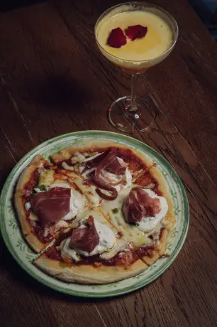 Plato de pizza y cóctel Nômadâ