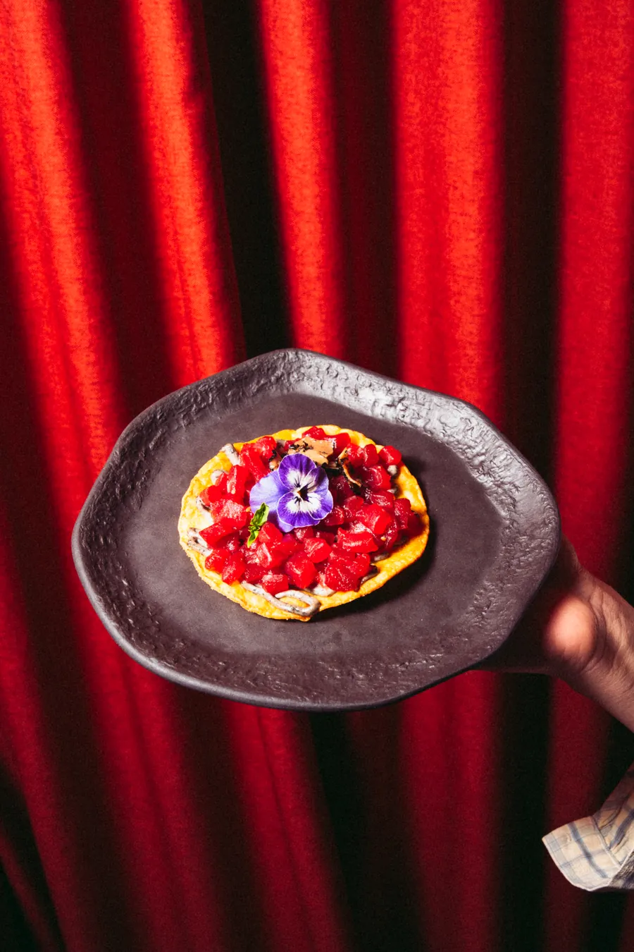 Toast with tomato and edible flowers from the menu at Nômadâ, Madrid